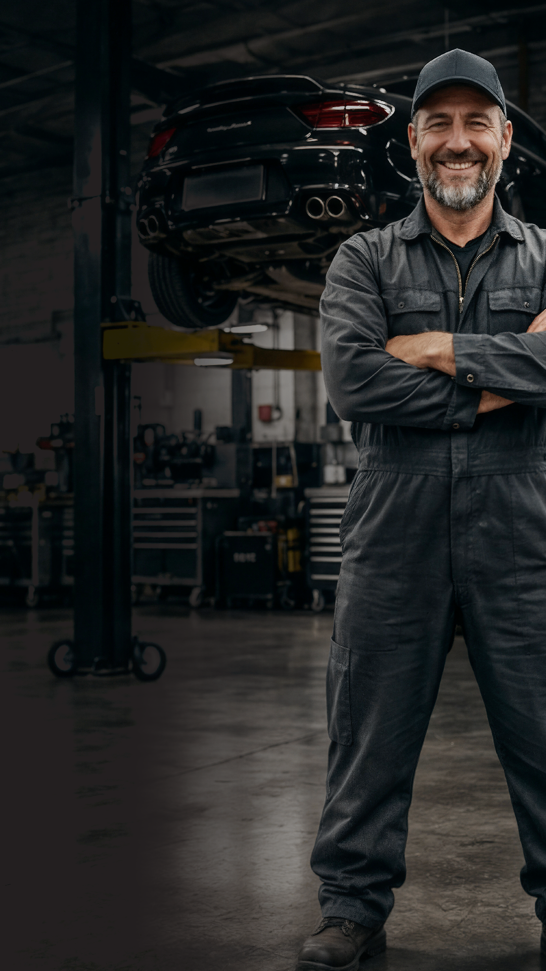 Smiling mechanic standing in front of a lifted car inside a modern workshop